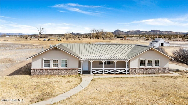 ranch-style home featuring brick siding, metal roof, a standing seam roof, a mountain view, and stucco siding