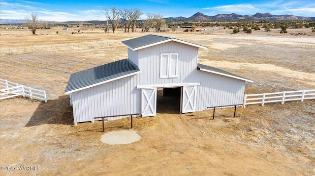 view of barn featuring a rural view, fence, and a mountain view