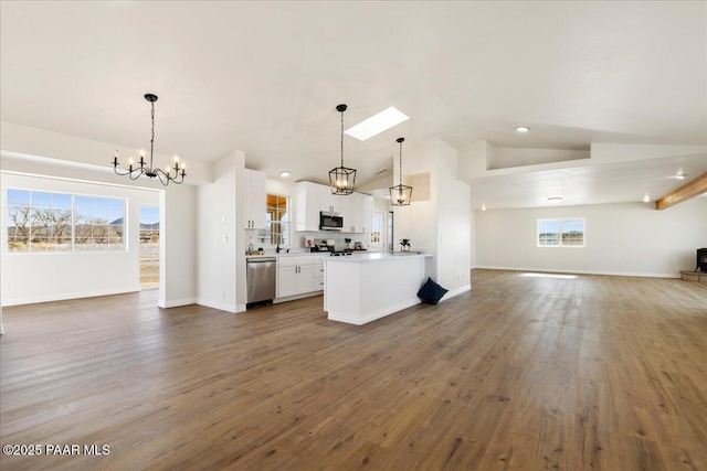 kitchen featuring stainless steel appliances, white cabinetry, open floor plan, vaulted ceiling, and decorative light fixtures