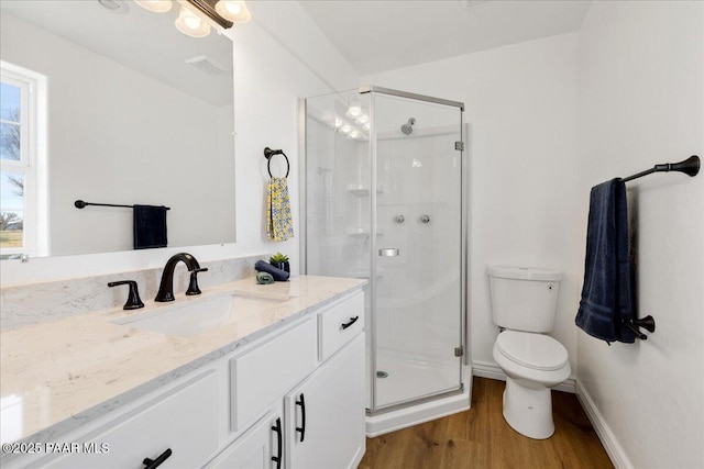 full bath with toilet, vanity, a shower stall, wood finished floors, and baseboards