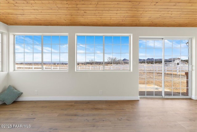 unfurnished room featuring light wood-style floors, lofted ceiling, wood ceiling, and baseboards