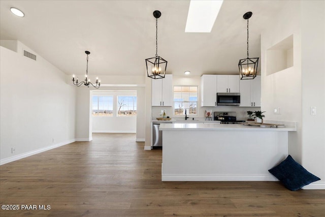 kitchen with white cabinets, appliances with stainless steel finishes, visible vents, and pendant lighting