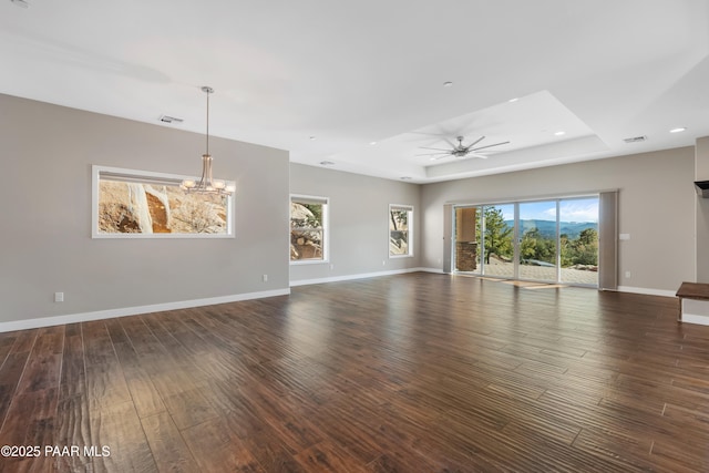 spare room with a tray ceiling, a healthy amount of sunlight, and dark hardwood / wood-style floors