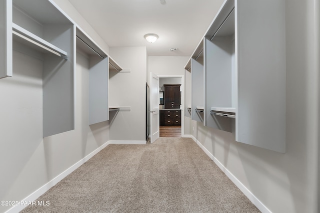 walk in closet featuring light colored carpet