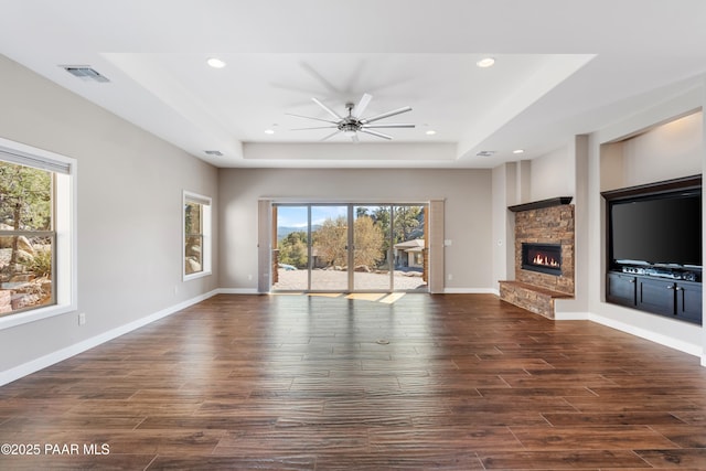 unfurnished living room featuring a fireplace, a tray ceiling, and ceiling fan