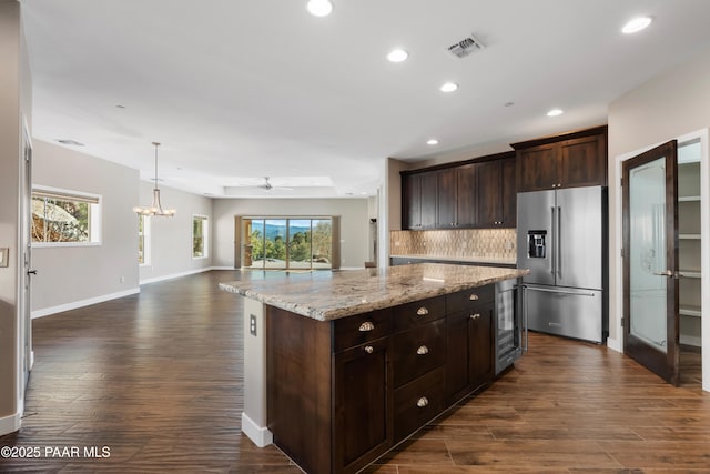 kitchen featuring ceiling fan with notable chandelier, a center island, light stone counters, and high end refrigerator