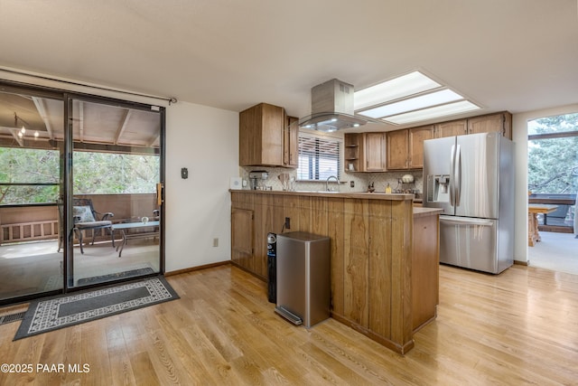 225 Sierra Rd, Sedona, AZ 86336 - kitchen featuring stainless steel refrigerator with ice dispenser, brown cabinets, light wood finished floors, a peninsula, and island range hood