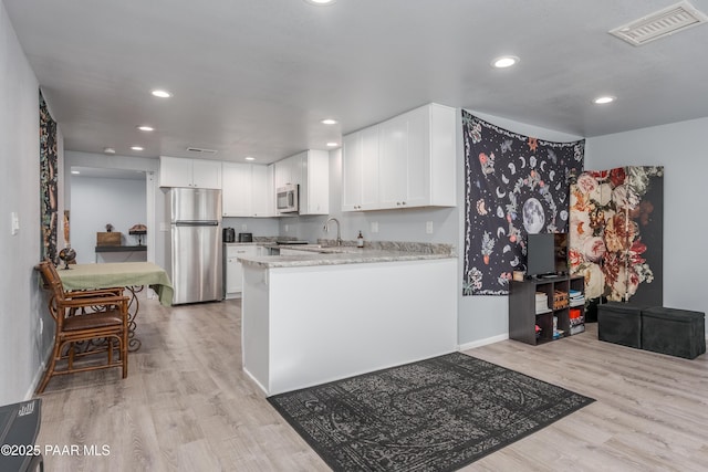 225 Sierra Rd, Sedona, AZ 86336 - kitchen with appliances with stainless steel finishes, light wood-style flooring, a sink, white cabinets, and recessed lighting