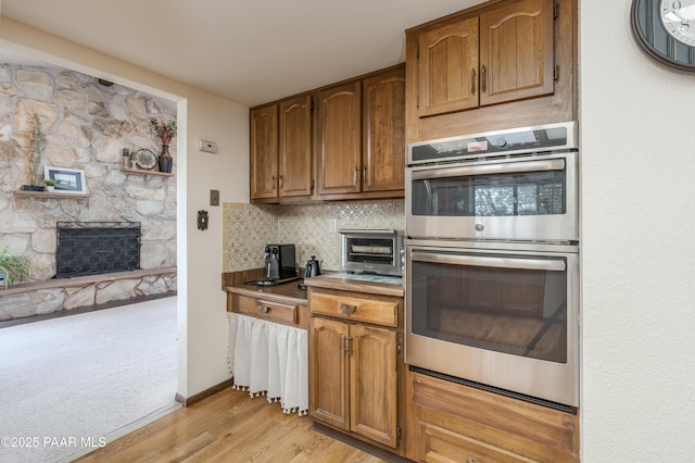 225 Sierra Rd, Sedona, AZ 86336 - kitchen with stainless steel double oven, backsplash, light wood finished floors, and brown cabinetry
