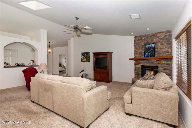 living room featuring a stone fireplace, ceiling fan, and light colored carpet