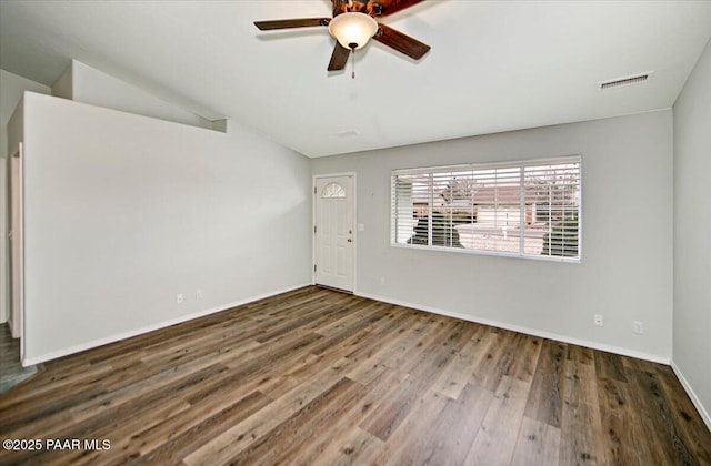 spare room with lofted ceiling, visible vents, ceiling fan, wood finished floors, and baseboards