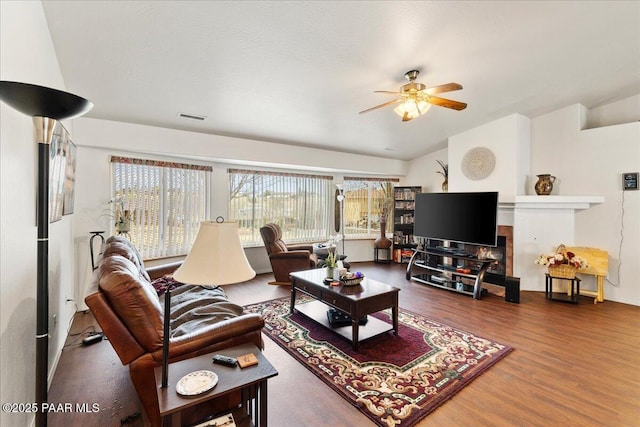 living room featuring ceiling fan, baseboards, wood finished floors, lofted ceiling, and visible vents