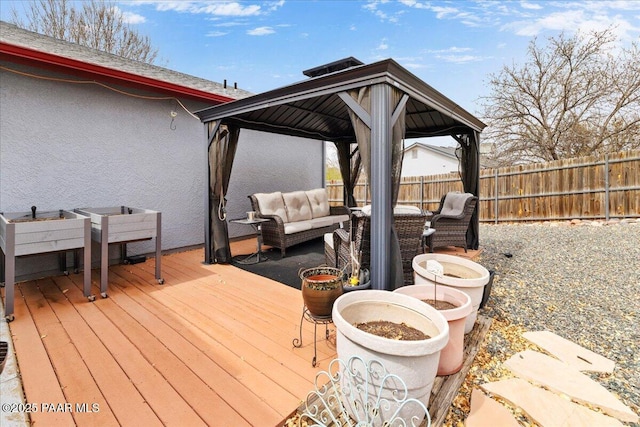wooden terrace with an outdoor hangout area, a gazebo, and a fenced backyard