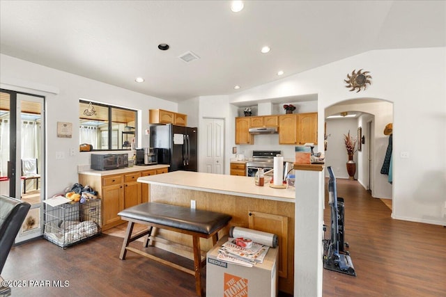 kitchen with a kitchen breakfast bar, dark wood finished floors, freestanding refrigerator, stainless steel electric stove, and under cabinet range hood