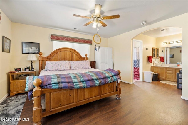 bedroom featuring arched walkways, baseboards, wood finished floors, and visible vents