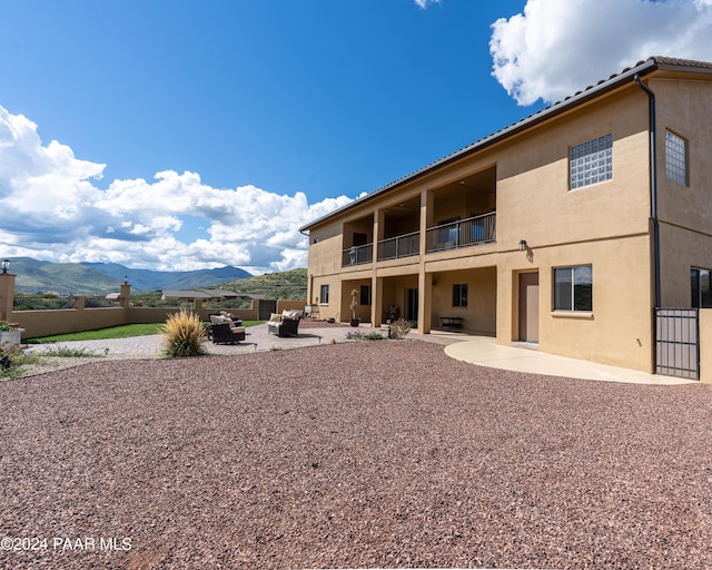 back of property featuring a mountain view, outdoor lounge area, a patio, and a balcony