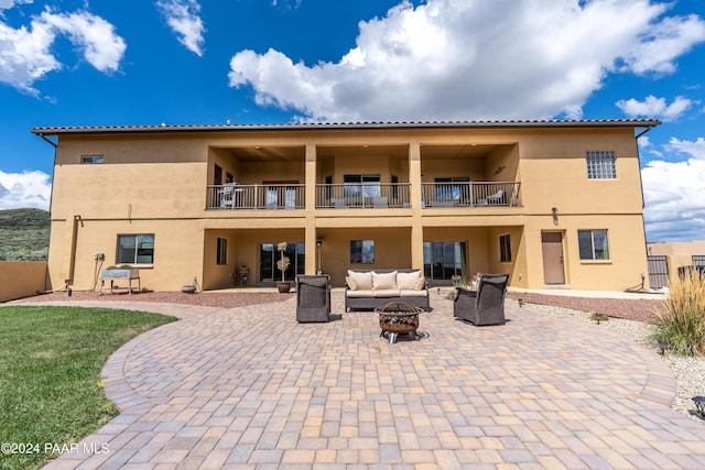 rear view of property featuring a balcony, an outdoor living space with a fire pit, and a patio area