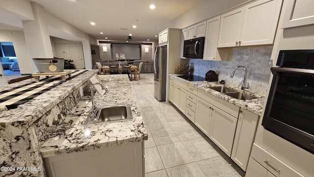 kitchen with black appliances, light stone counters, white cabinetry, and sink