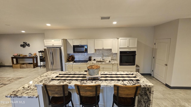 kitchen with black appliances, white cabinets, light stone countertops, and sink