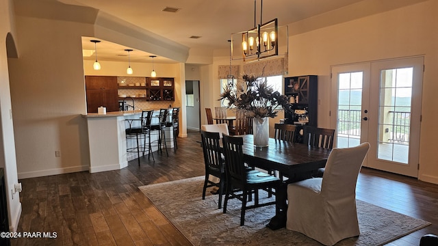 dining space featuring french doors, dark hardwood / wood-style floors, and a notable chandelier