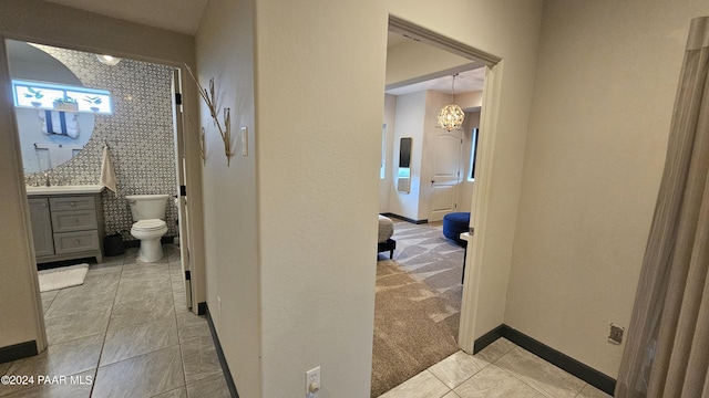 hall featuring light colored carpet and a notable chandelier