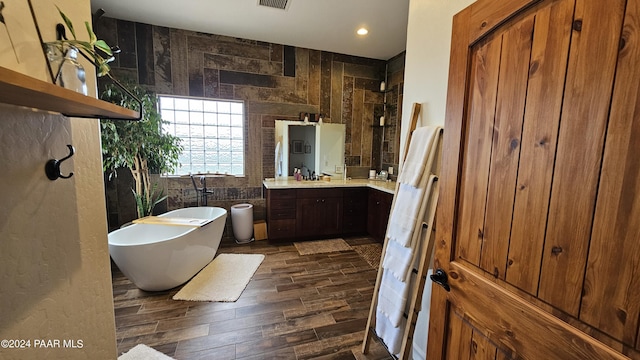 bathroom with vanity, wood-type flooring, a bath, and tile walls