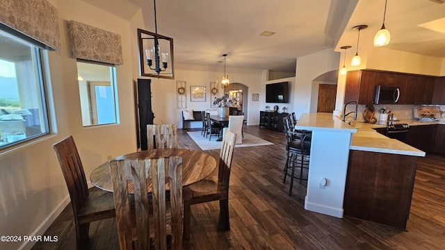 dining space with lofted ceiling, dark wood-type flooring, and an inviting chandelier