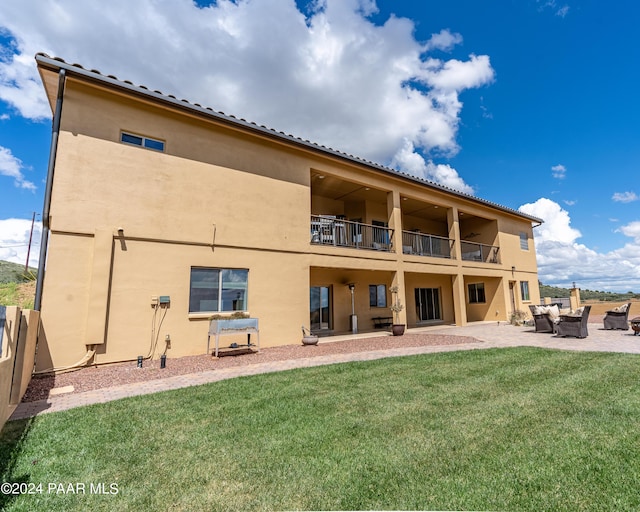 rear view of house with a yard, a balcony, and a patio