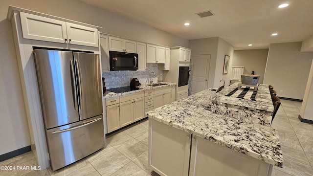 kitchen with white cabinets, a kitchen island, and black appliances