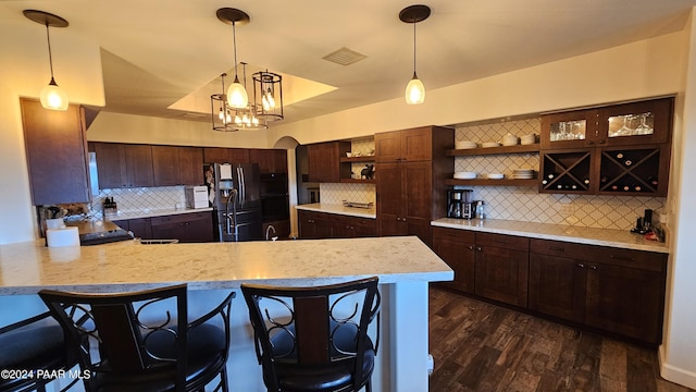 kitchen featuring backsplash, stainless steel fridge, dark hardwood / wood-style flooring, and hanging light fixtures