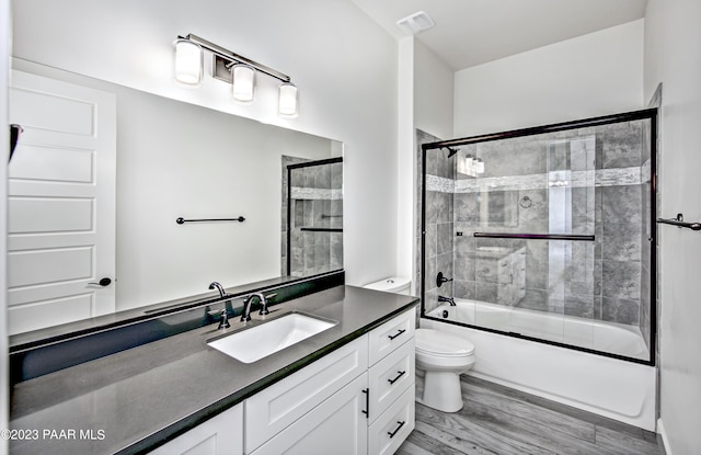 6267 W Omar Rd, Prescott, AZ 86305 - full bath featuring visible vents, bath / shower combo with glass door, toilet, wood finished floors, and vanity