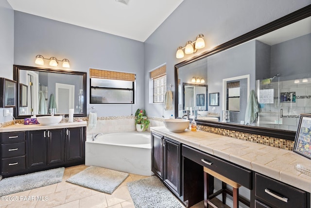 bathroom with tile patterned floors, a garden tub, two vanities, a sink, and a tile shower