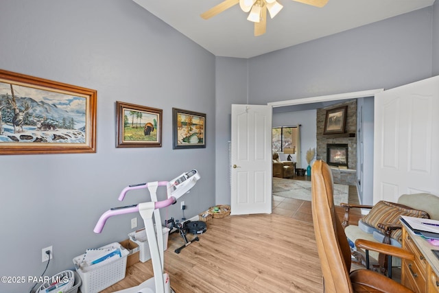 office space featuring light wood-style flooring, ceiling fan, and a fireplace