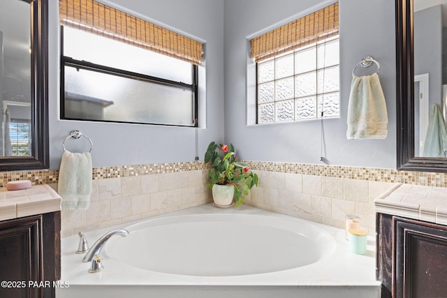 full bath with tasteful backsplash, a bath, and vanity