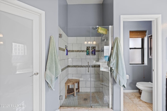 bathroom with tile patterned floors, a stall shower, toilet, and baseboards