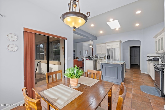 dining space featuring recessed lighting, arched walkways, a skylight, and tile patterned floors