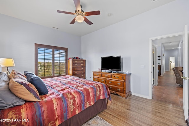 bedroom with baseboards, visible vents, light wood finished floors, and ceiling fan