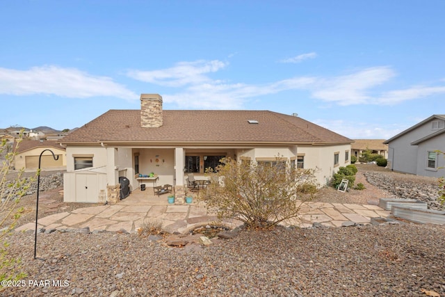 rear view of property featuring a patio, a chimney, and stucco siding