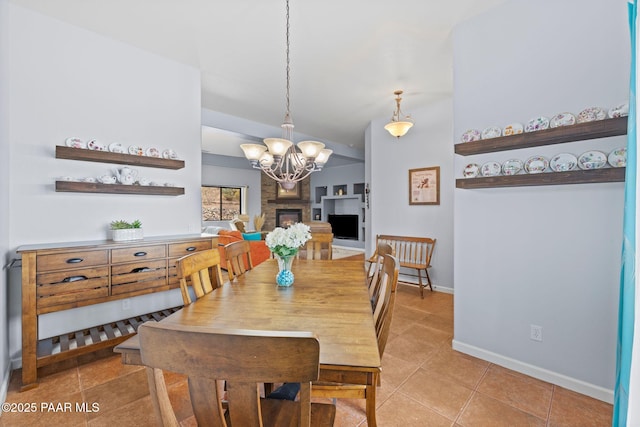 dining room with a glass covered fireplace, baseboards, a notable chandelier, and light tile patterned flooring