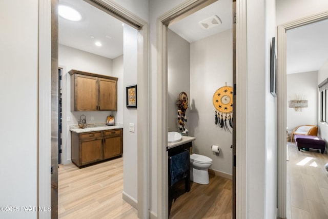 bathroom with toilet, vanity, and hardwood / wood-style flooring