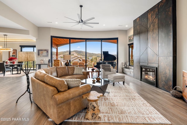 living room featuring ceiling fan, light hardwood / wood-style floors, a mountain view, and a fireplace