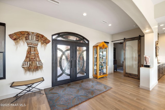 entryway featuring french doors, a barn door, and light hardwood / wood-style flooring