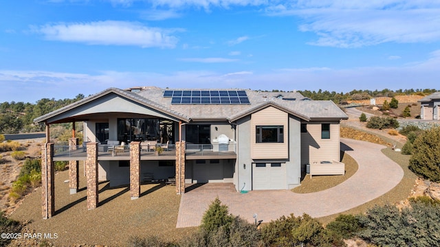 back of property featuring solar panels and a garage