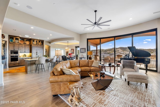 living room with ceiling fan with notable chandelier and light hardwood / wood-style floors