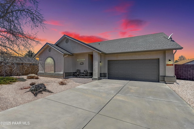 view of front of property with a garage, concrete driveway, roof with shingles, fence, and stucco siding