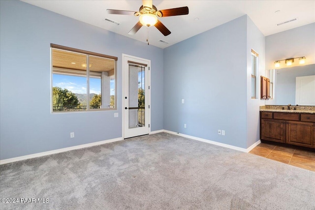 carpeted spare room featuring sink and ceiling fan