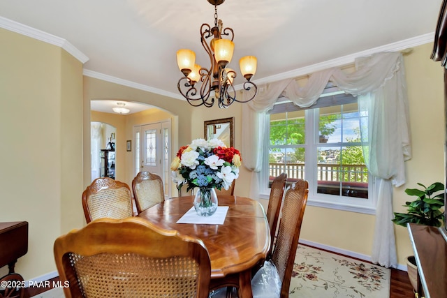 dining space featuring ornamental molding, arched walkways, a healthy amount of sunlight, and a notable chandelier