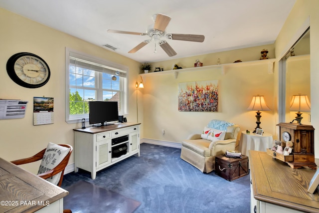 interior space with baseboards, dark colored carpet, ceiling fan, and visible vents