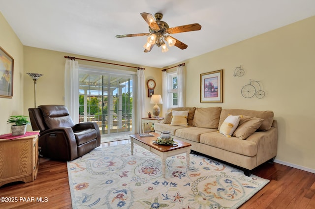 living room with baseboards, ceiling fan, and wood finished floors