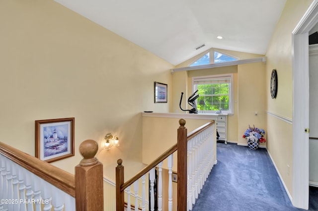 corridor featuring an upstairs landing, visible vents, baseboards, dark carpet, and vaulted ceiling